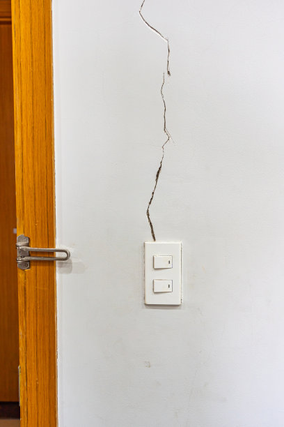 白色裂缝墙和灯光开关的垂直照片图片下载