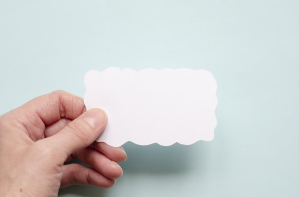 女性手拿一张白纸，天蓝色背景。图片下载