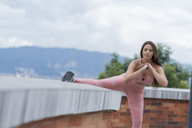 美丽的女孩表演她的伸展，而在她的房子的阳台上做她的热身穿着她的运动服图片下载