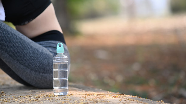 一瓶水和运动员在户外锻炼后坐和休息。图片下载