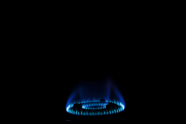 煤气灶上有蓝色火焰的库存照片，以黑色为背景，聚焦在物体上。图片下载