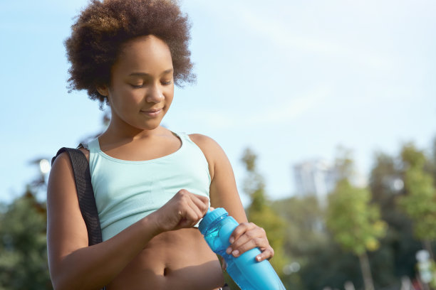 可爱的小女孩拿着一瓶水站在街上图片下载