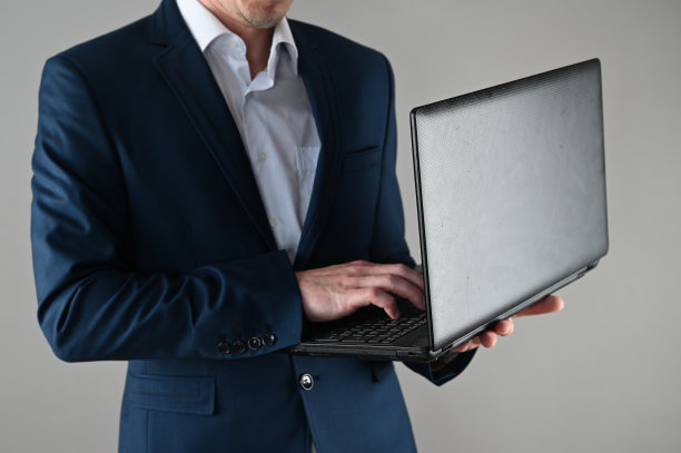 一个穿西装的人手里拿着一台笔记本电脑，背景是孤立的图片下载