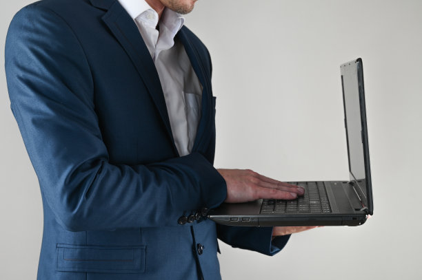 一个穿西装的人手里拿着一台笔记本电脑，背景是孤立的图片下载