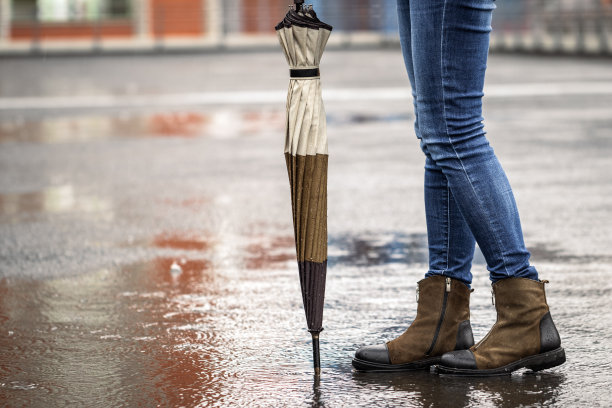 下雨的时候，女人撑着伞站在城市街道上图片下载
