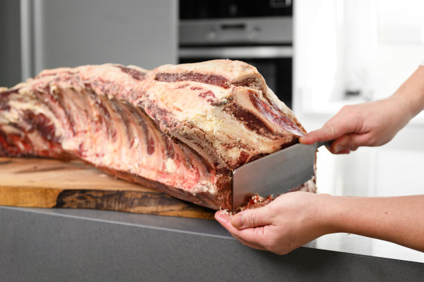 厨师正在准备上等肋排牛排，从一个大的上等牛排烤多骨。肉放在一块木板上，木板放在一个现代化的厨房柜台上。高质量的照片图片下载