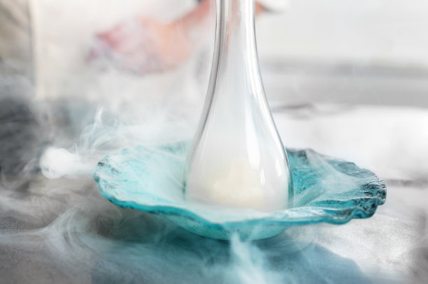 一位优秀的餐厅厨师，正在用精致的厨房用具熏着盘子。高质量的照片。图片下载