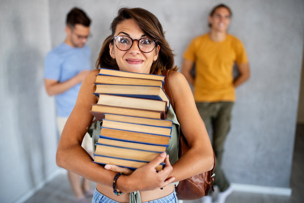 一个微笑的大学生在看书的照片图片下载