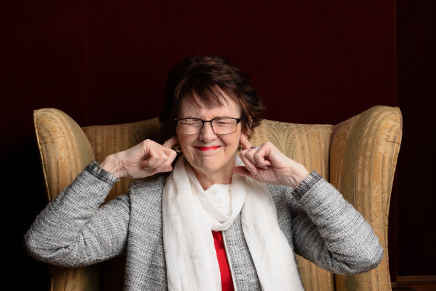 一个闭着眼睛，用手指堵住耳朵，愁眉苦脸的女人。图片下载