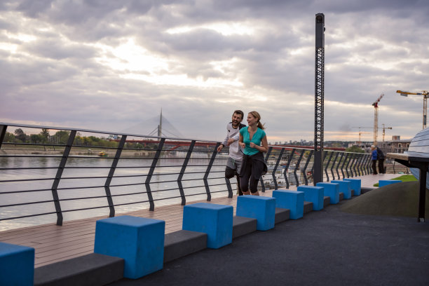 年轻的体育夫妇正在桥上跑步。早上慢跑。图片下载