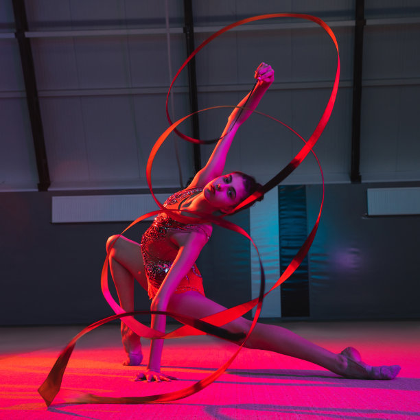 年轻优雅的女子体操运动员在霓虹灯的彩色背景下孤立图片下载