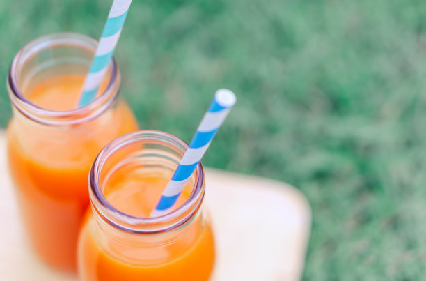 特写俯视图玻璃胡萝卜汁与绿草背景，选择性聚焦图片下载