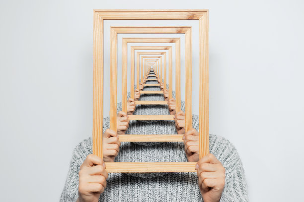 神秘的超现实主义视觉错觉，年轻人在灰色背景上持有框架。图片下载