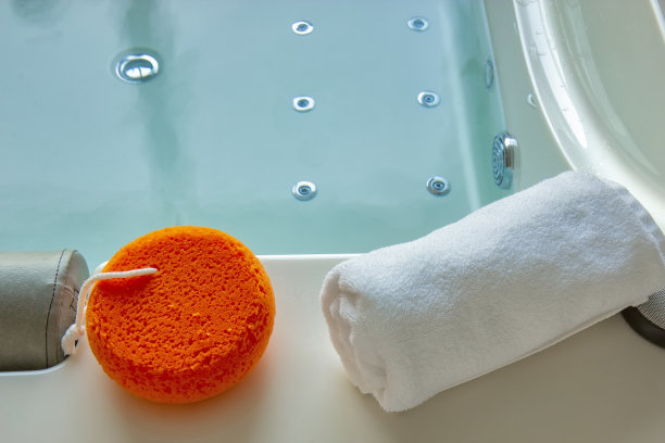 橙色的海绵和毛巾放在热水浴缸里图片下载