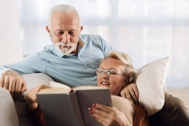 一对成熟的夫妇在客厅的沙发上看书图片下载