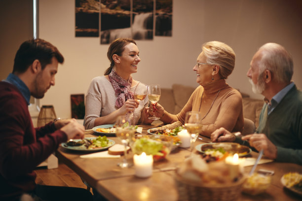幸福的女人在家庭晚宴上喝酒。图片下载