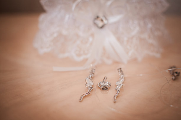 白色吊袜带耳环和吊坠躺在木桌上图片下载