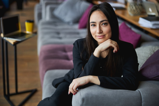 有魅力的年轻女子坐在商务中心的沙发上图片下载