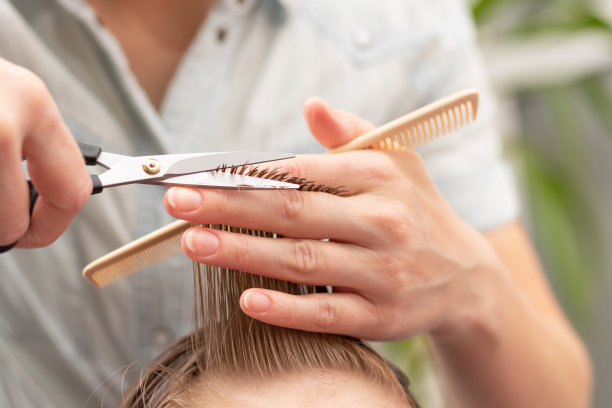 在第二次封锁期间，一位母亲用梳子和剪刀在家里为儿子做了一个时尚的发型。有选择性的重点图片下载