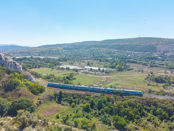 蓝色和白色的车厢在森林和山脉中穿行。一列火车在山口的鸟瞰图，城际高速列车的照片，高速列车在一个美丽的风景。山脉间的火车图片下载