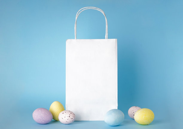 彩色的复活节彩蛋和蓝色背景的纸袋，文字空间图片下载
