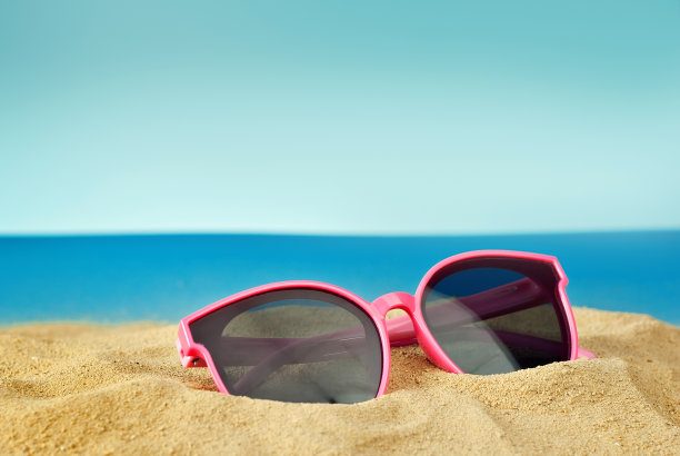 近距离看沙滩上的粉红色眼镜。在蓝天碧水的背景下，海滩上的眼镜。夏季，海洋和度假概念。图片下载