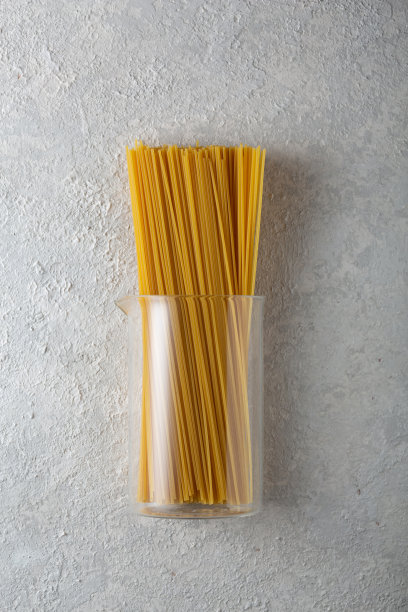 生的意大利通心粉通心粉在一个玻璃烧瓶在一个轻混凝土背景图片下载