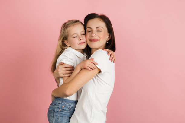 快乐的女人和小女孩，母亲和女儿孤立在粉红色的背景下。图片下载