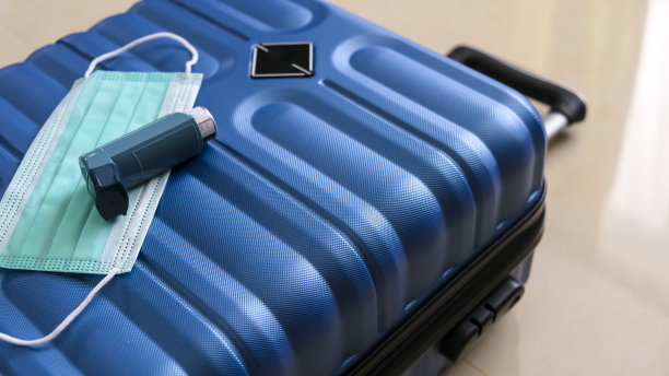 covid - 19大流行期间旅行所需的行李箱、口罩和吸入器齐全。概念假期和旅行。横幅的尺寸。复制空间，选择性聚焦。浅景深图片下载