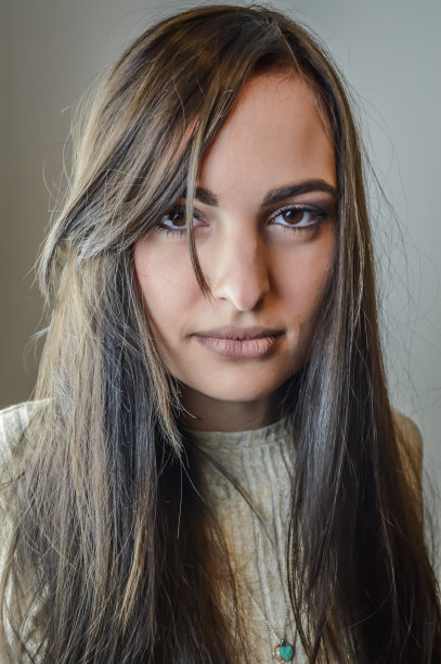 一个美丽的年轻女子的肖像与一个强烈的和迷人的凝视长棕色头发图片下载
