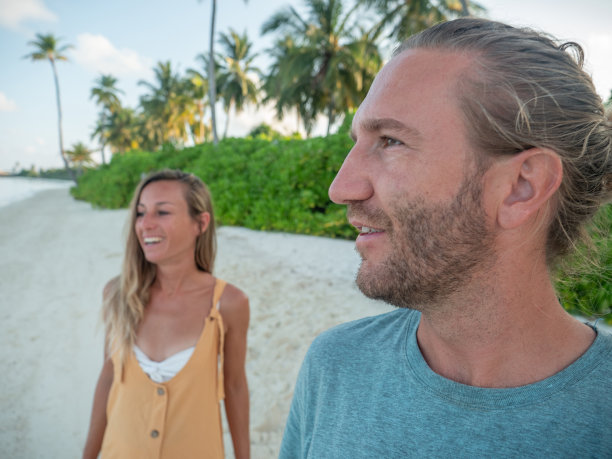 在日落的热带海滩上的夫妇的侧视图图片下载