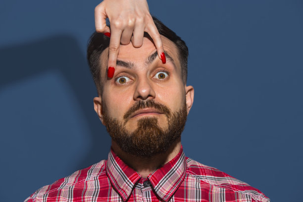 女性的手张开的眼睛，年轻的胡子英俊的男子在蓝色的背景图片下载