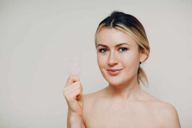 年轻女性做面部刮痧按摩治疗图片下载