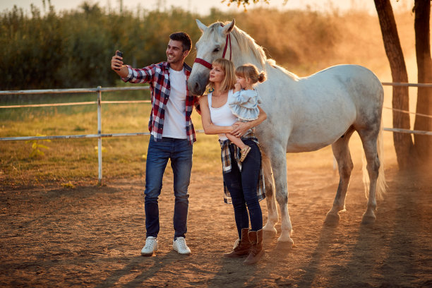 微笑的家庭享受乡村马场和自拍。图片下载
