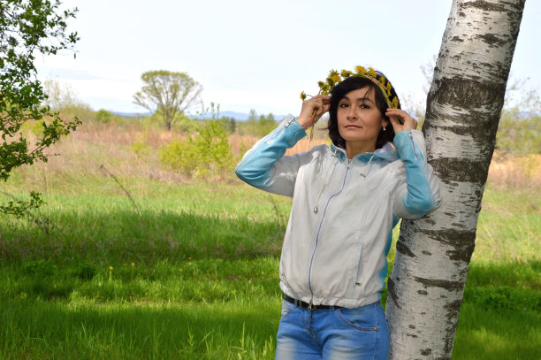 一个45岁的俄罗斯妇女的肖像与手工制作的蒲公英花环在一个领域。春天,俄罗斯图片下载