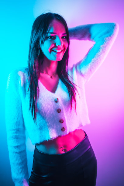 派对生活在夜总会与粉色蓝色霓虹灯，一个年轻的黑发白种人有乐趣在白色羊毛衫图片下载