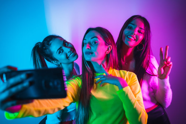 朋友们在迪斯科舞厅里狂欢，在蓝色和粉色的霓虹灯下开心地拍照留念图片下载