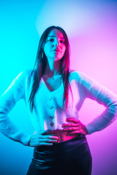 派对生活在夜总会与粉色蓝色霓虹灯，一个年轻的黑发白种人有乐趣在白色羊毛衫图片下载