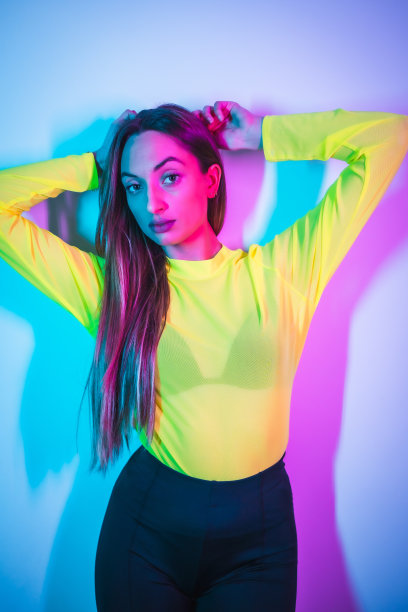 派对生活在夜总会与粉红色的蓝色霓虹灯，一个年轻的金发白人女孩的肖像在黄色t恤的乐趣图片下载