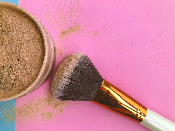 化妆刷和粉放在一个棕色罐子里。适合深色皮肤女孩的爽身粉。用于在白色纹理背景上勾画轮廓的粉末图片下载