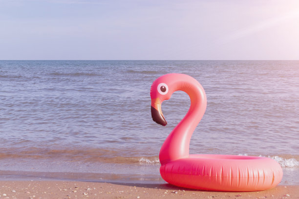 夏天出售。粉红色的充气火烈鸟在蓝色的海水为海夏季海滩的背景。最小的夏天的概念。图片下载