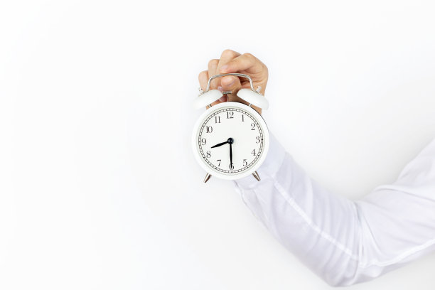 孤立的商人手上拿着一个白色背景的闹钟。图片下载