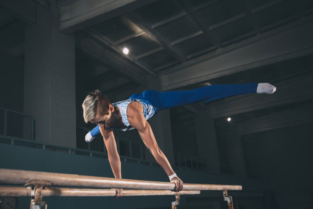 小男子体操运动员在体操馆里训练，灵活、活跃。白种人健康的小男孩，运动员穿着运动服练习力量，平衡。图片下载
