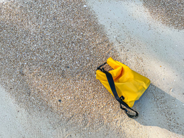俯视图的角度和特写生动的防水袋在海滩上与棕色的砾石和白色的沙子背景。夏季或旅行的概念和想法。图片下载