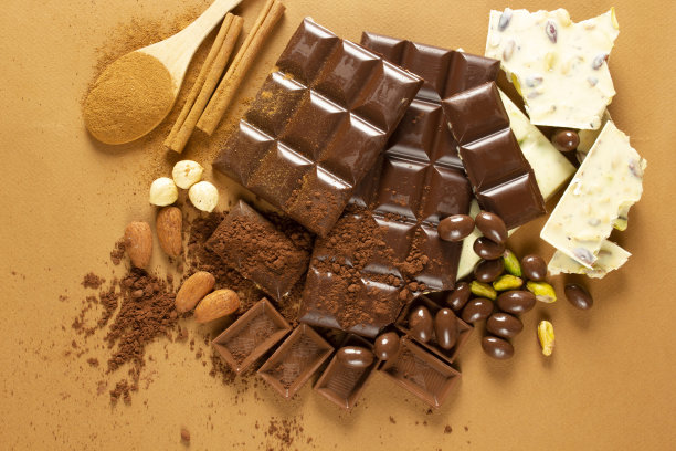 白巧克力和牛奶巧克力。杏仁、开心果、榛子。背景,纹理。图片下载