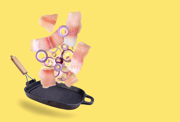 一块飞鱼排掉进了锅里。飞行运动在烹饪过程中的影响。黄色背景上的孤立物体。飞行的食物图片下载
