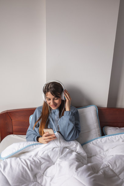 女人戴着耳机用智能手机上网图片下载