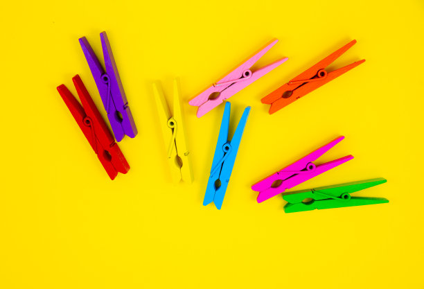 黄色背景上的彩色木衣夹。关闭，复制空间。极简主义，原创和创意的照片。是另一个。个性的概念。图片下载