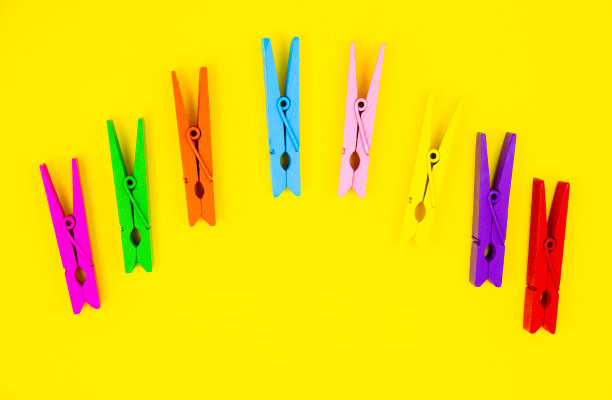黄色背景上的彩色木衣夹。关闭，复制空间。极简主义，原创和创意的照片。是另一个。个性的概念。图片下载