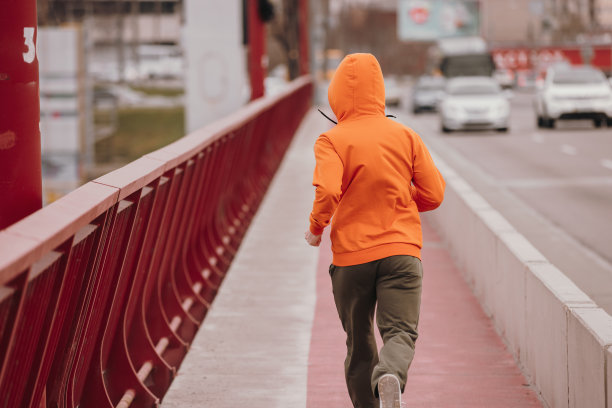 穿橙色连帽衫的男人在桥上奔跑，后视镜图片下载